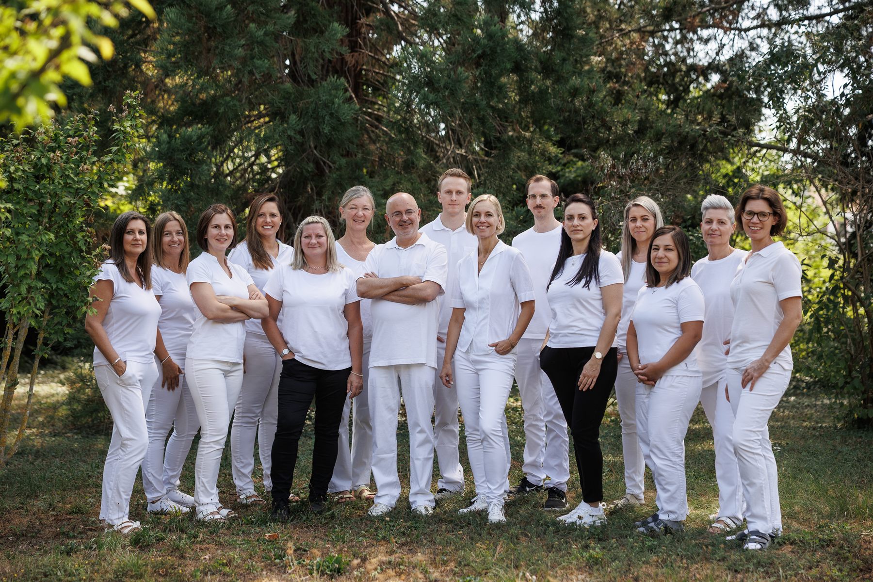 Das gesamte Team des Diagnosezentrums Neunkirchen steht in weißer Berufskleidung nebeneinander im Grünen